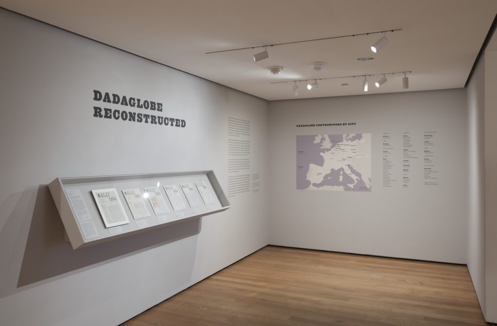 Opening room to exhibition that includes wall vinyl of the title "Dadaglobe Reconstructed" and a map of where participating artists came from.